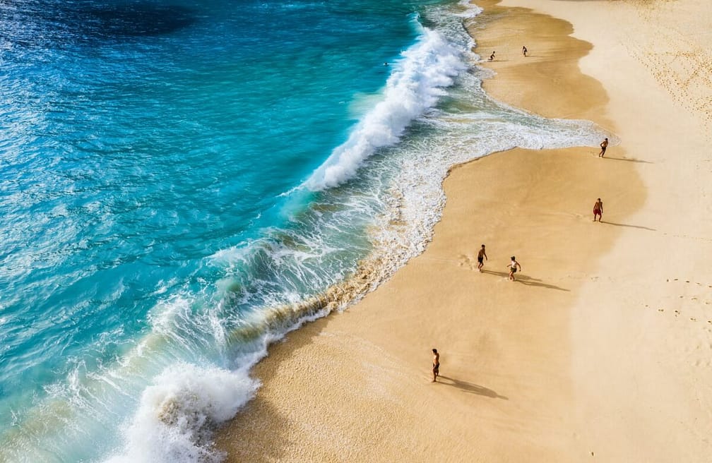 People on the beach on Bali, Indonesia. Vacation and adventure. Beach and large waves.