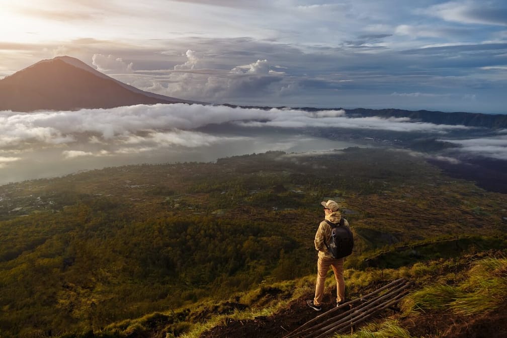 Man tourist looks at the sunrise on the volcano Batur on the island of Blai in Indonesia. Hiker man