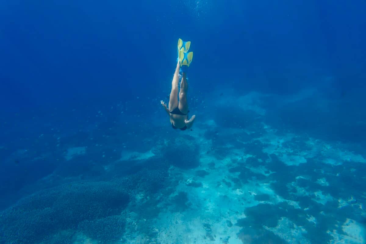 Woman with fins and snorkel diving under water