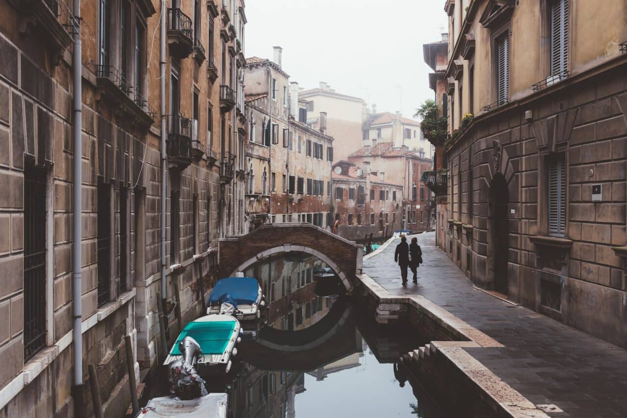 Rear view of couple strolling along canal waterfront, Venice, Italy